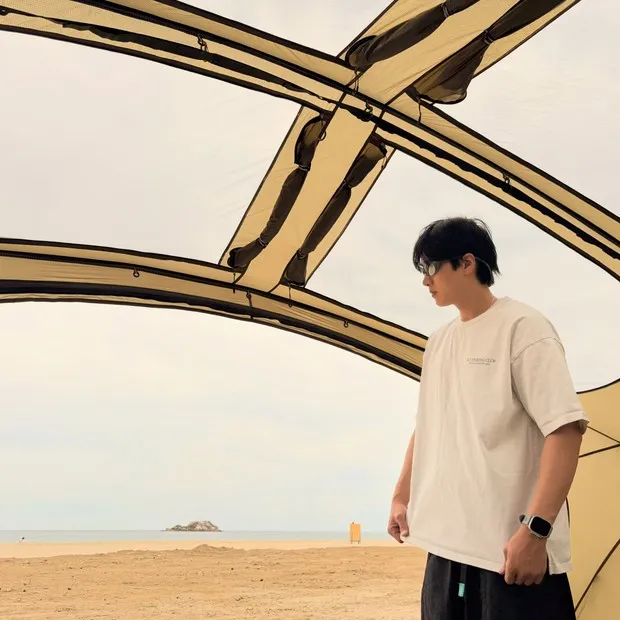 Potret Ahn Bo Hyun berkemah di tepi pantai/ Foto: instagram.com/bohyunahn Ahn Bo Hyun displays his natural charm with a casual look while enjoying a beach camping experience.