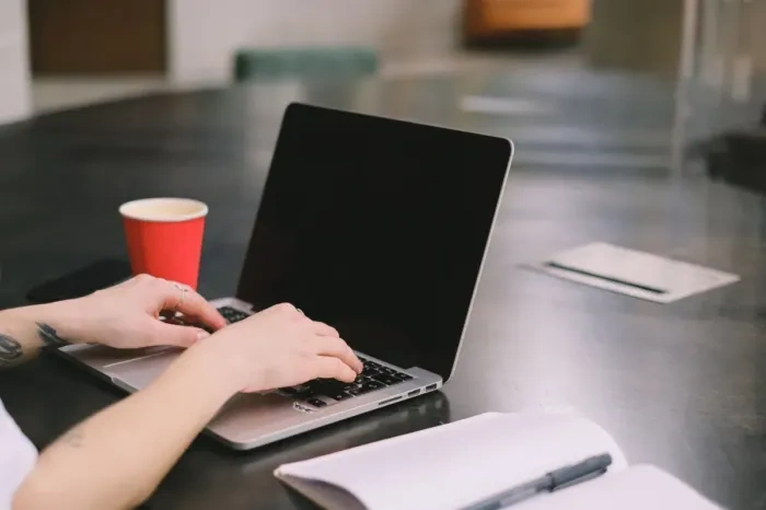 Seorang pekerja lepas sedang menyusun penawaran jasa yang sederhana di laptop