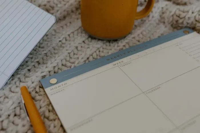 Blogger menyusun jadwal menulis mingguan di meja kerja