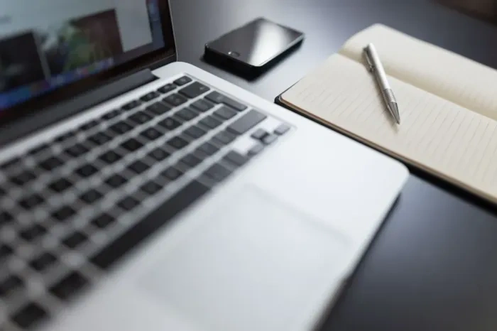 Professional recording daily work results in a notebook near a laptop
