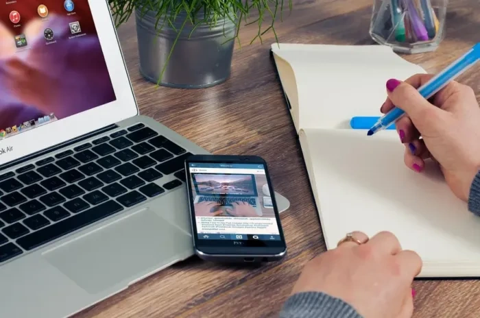 Tangan menulis draf awal di buku catatan di dekat laptop